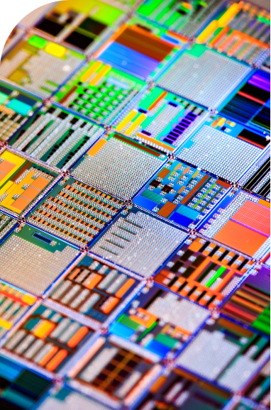 mask | Iterators A close-up photo showing a colorful, reflective silicon wafer featuring a dense grid of microchip circuits.
